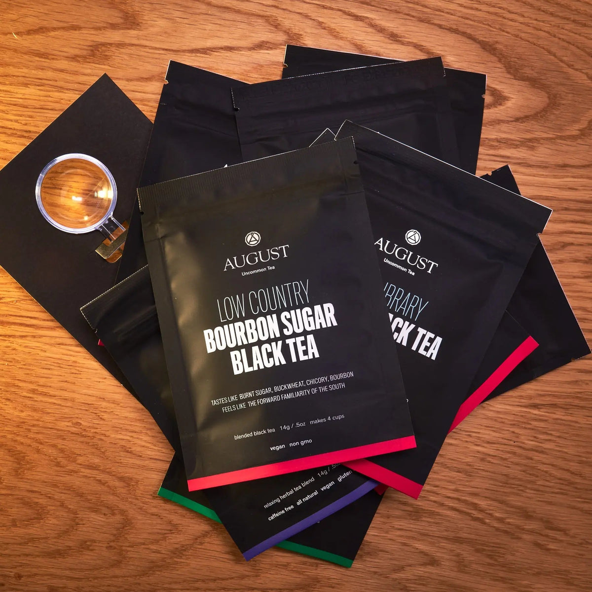 Assortment of August Uncommon Tea loose leaf sample pouches arranged on a wooden surface