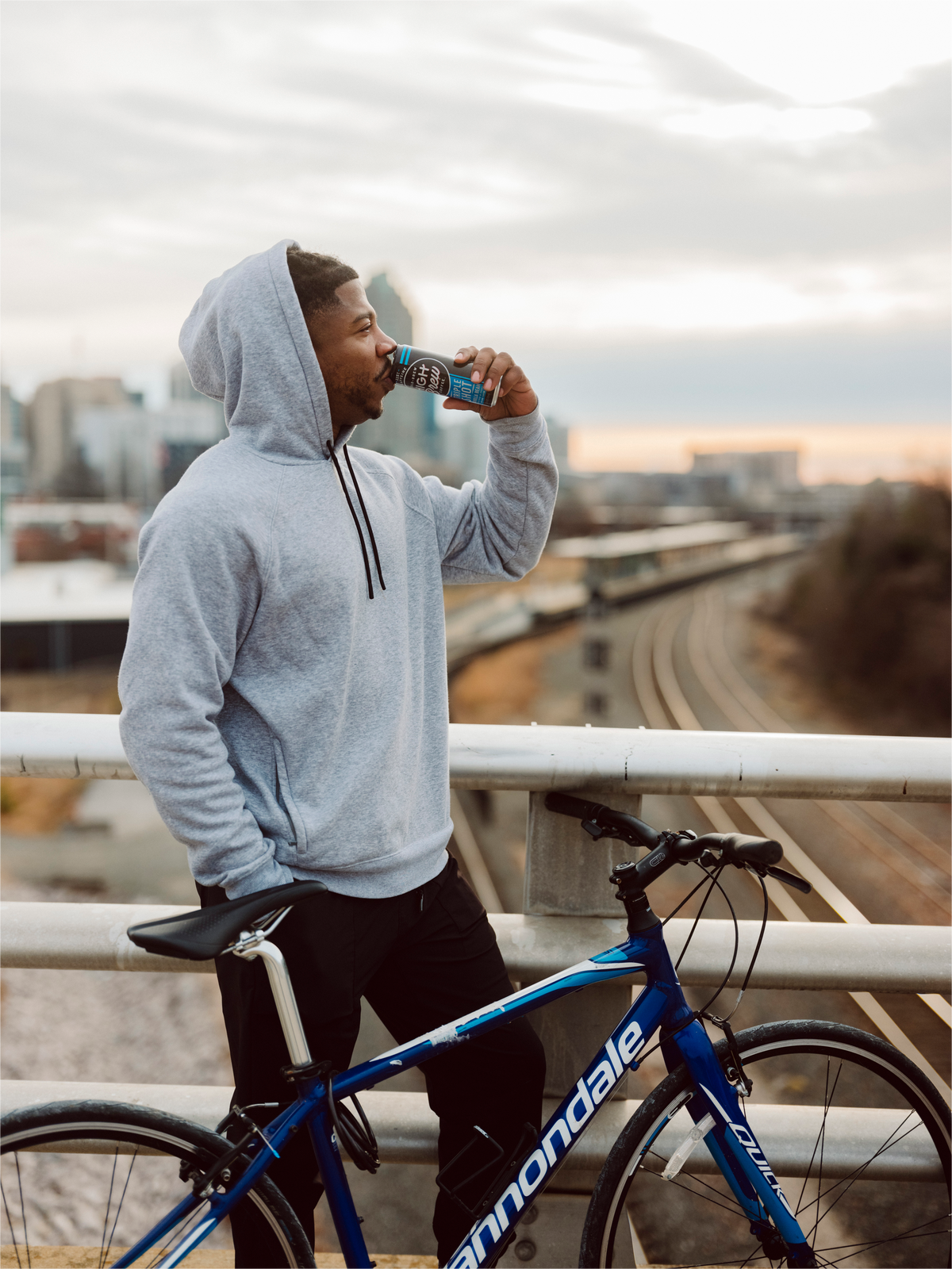 Person enjoying High Brew Vanilla Bean Triple Shot Cold Brew Coffee outdoors near a bicycle