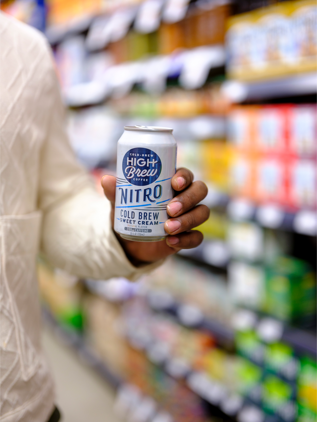 Person holding a High Brew Nitro Sweet Cream Cold Brew Coffee can while shopping