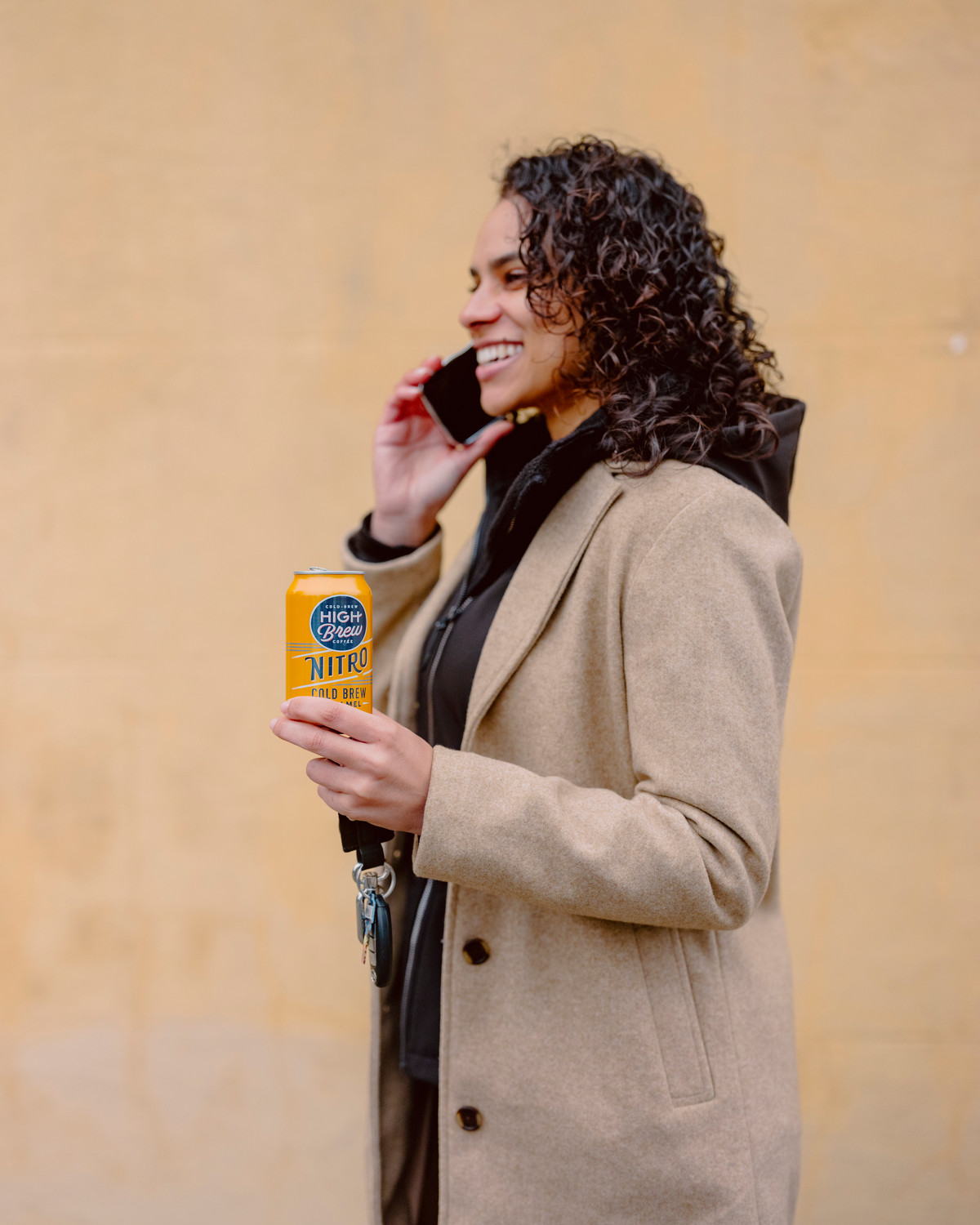 Person holding a High Brew Nitro Caramel Cold Brew Coffee can while walking outdoors