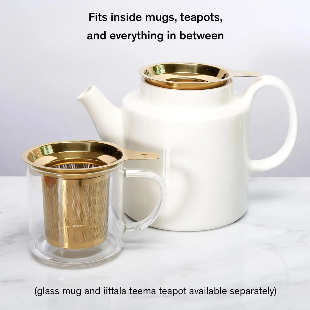 Gold stainless steel tea infuser inside white glass teapot with loose leaf tea

