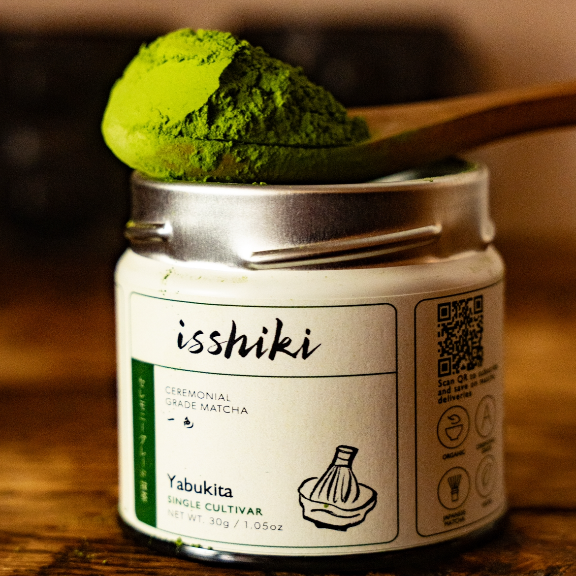 Close-up of Isshiki Yabukita matcha tin with bright green matcha powder on a wooden spoon