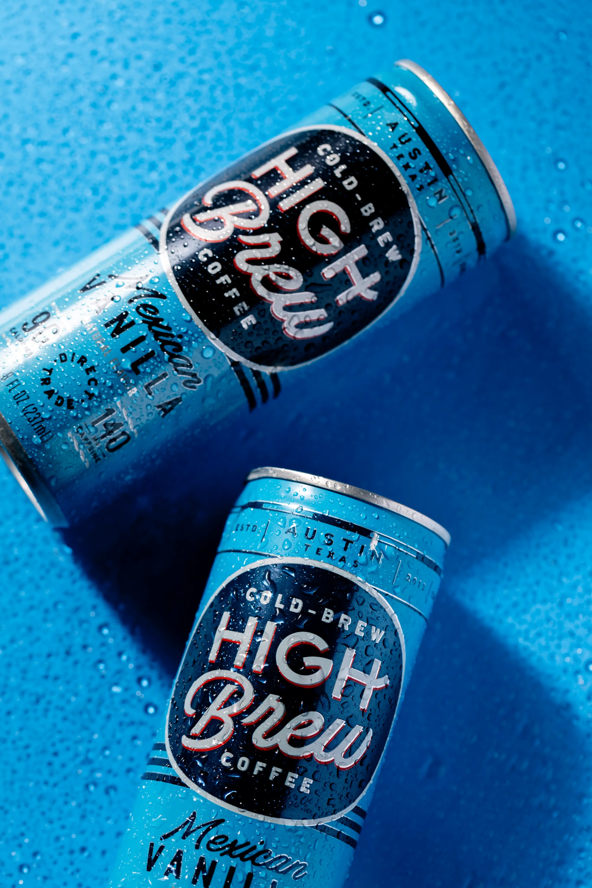 Two blue High Brew Mexican Vanilla Cold Brew Coffee cans displayed on a blue textured surface