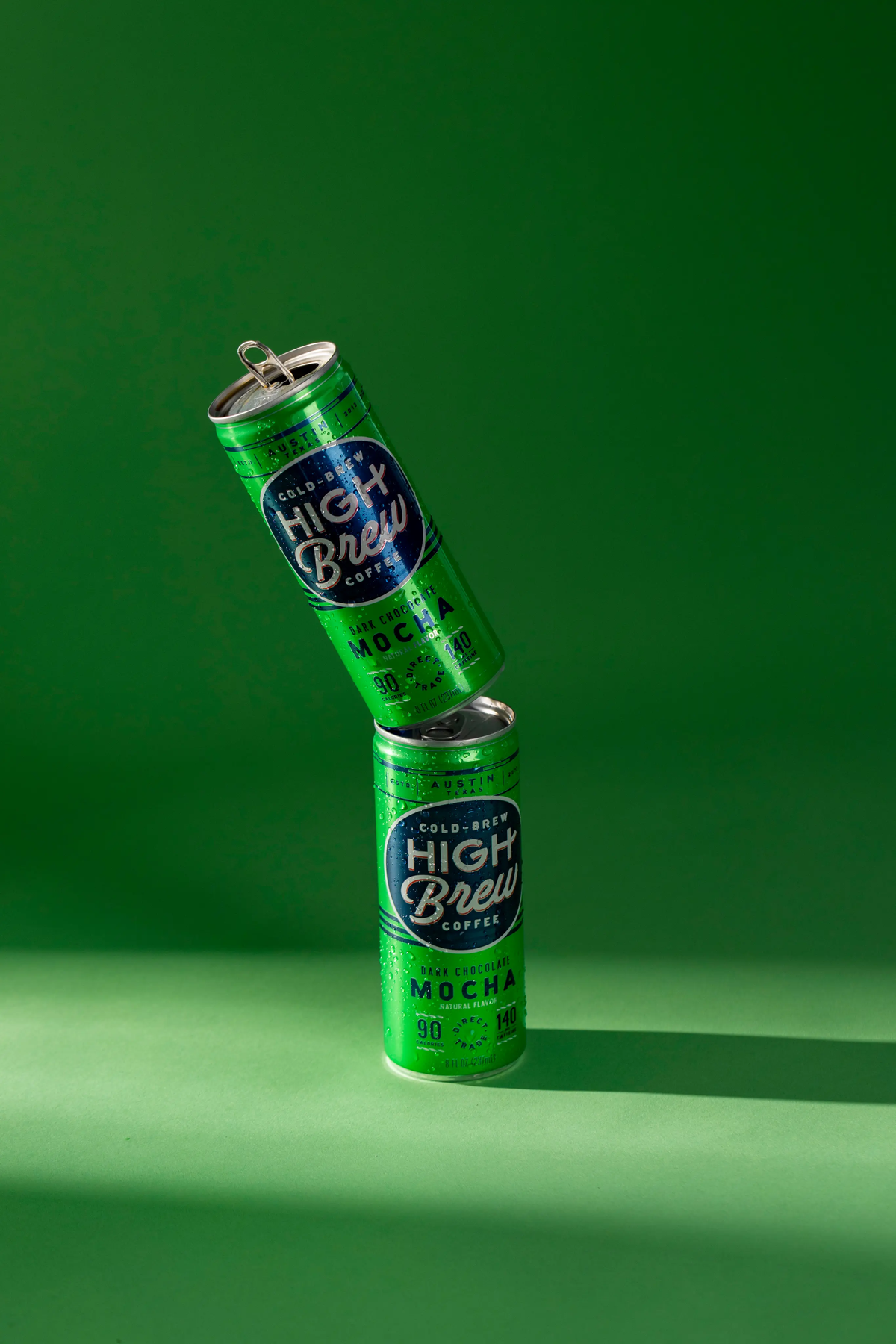 Two High Brew Dark Chocolate Mocha cold brew coffee cans stacked against a green background