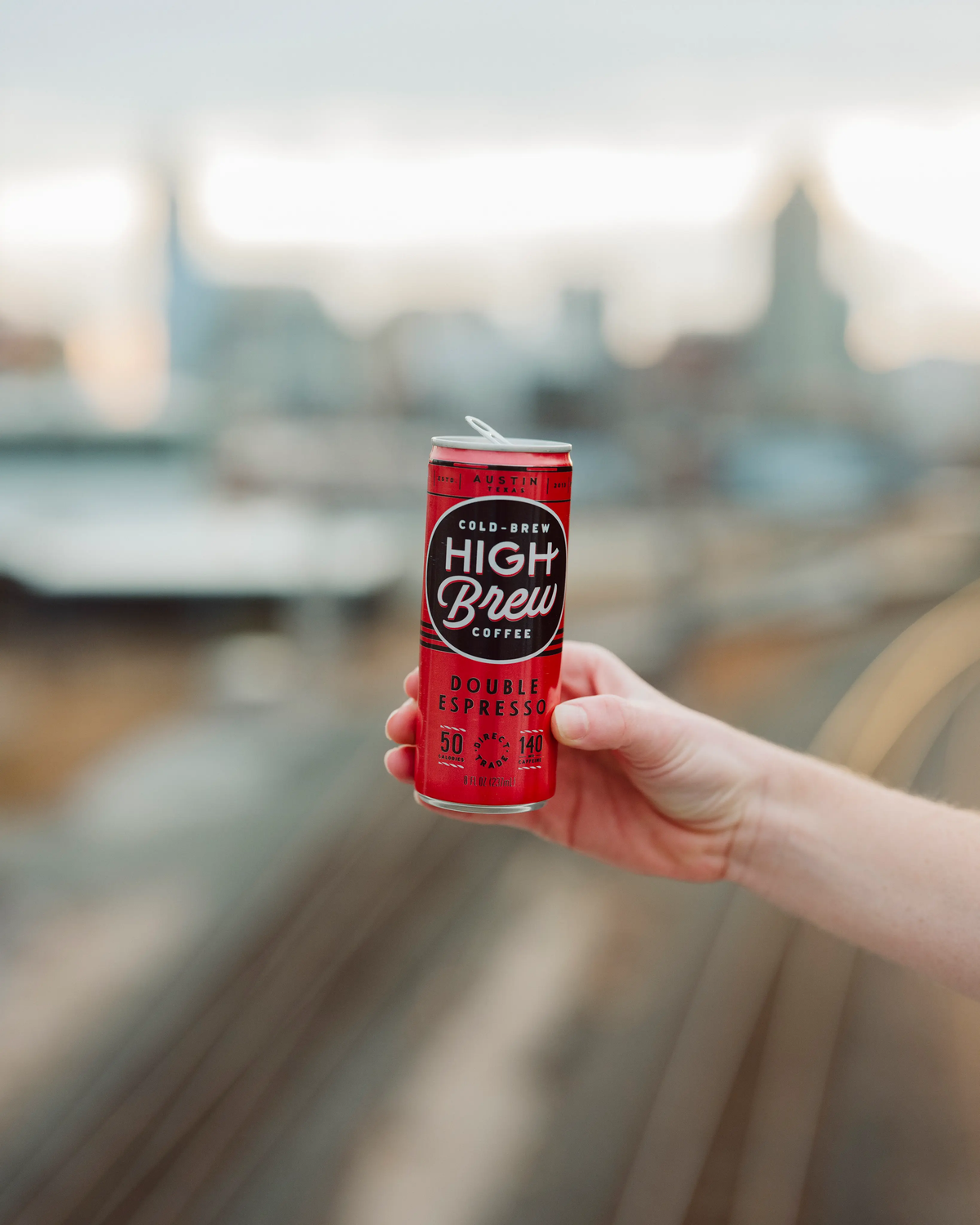 Person holding a red High Brew Double Espresso cold brew coffee can outdoors