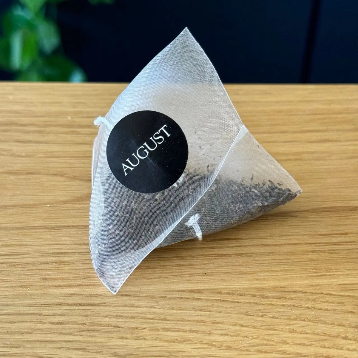 August Black Gold black tea in a pyramid-shaped tea bag with visible tea leaves