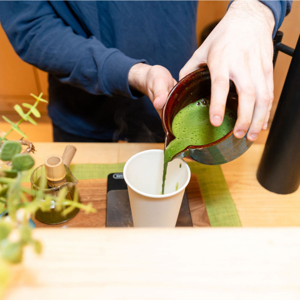 Pouring freshly prepared Japanese matcha into a white cup