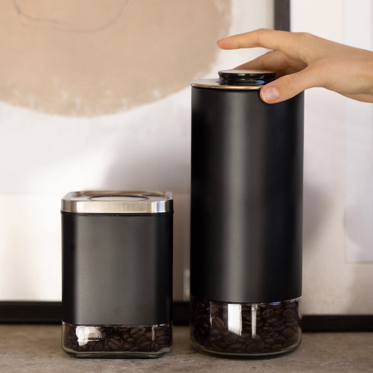 Kaffé black stainless steel coffee storage containers displayed on a modern kitchen countertop