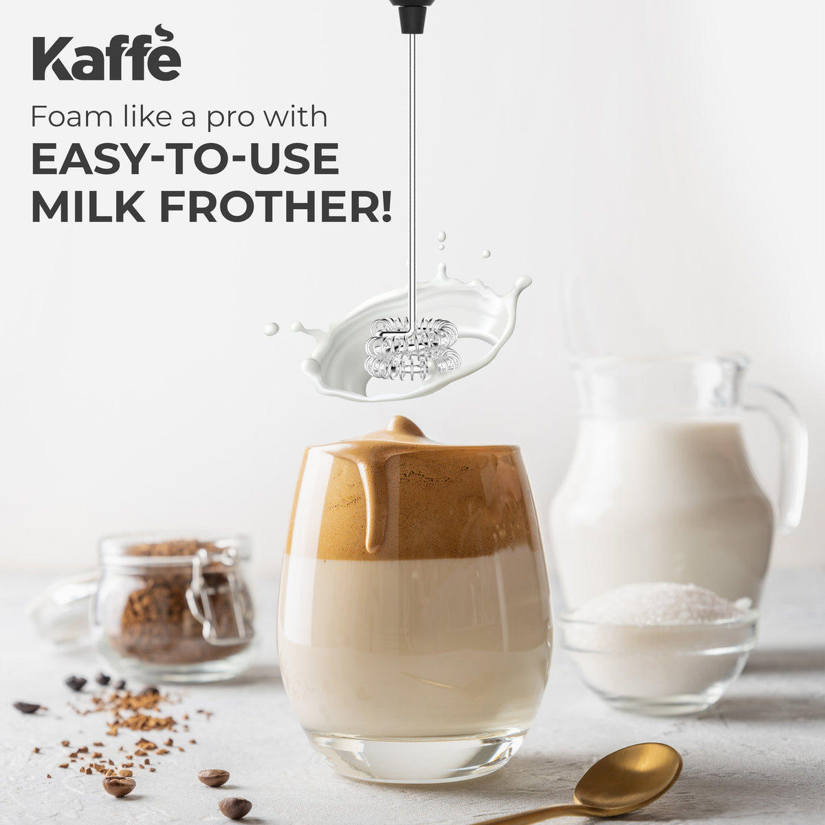 Kaffé stainless steel handheld milk frother displayed with countertop stand and coffee accessories