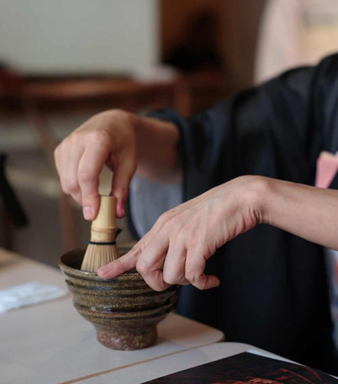 Traditional Japanese matcha preparation using a bamboo whisk and ceramic bowl