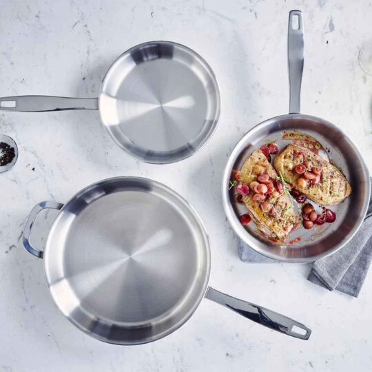 Overhead view of Alva stainless steel frying pans alongside a prepared meal