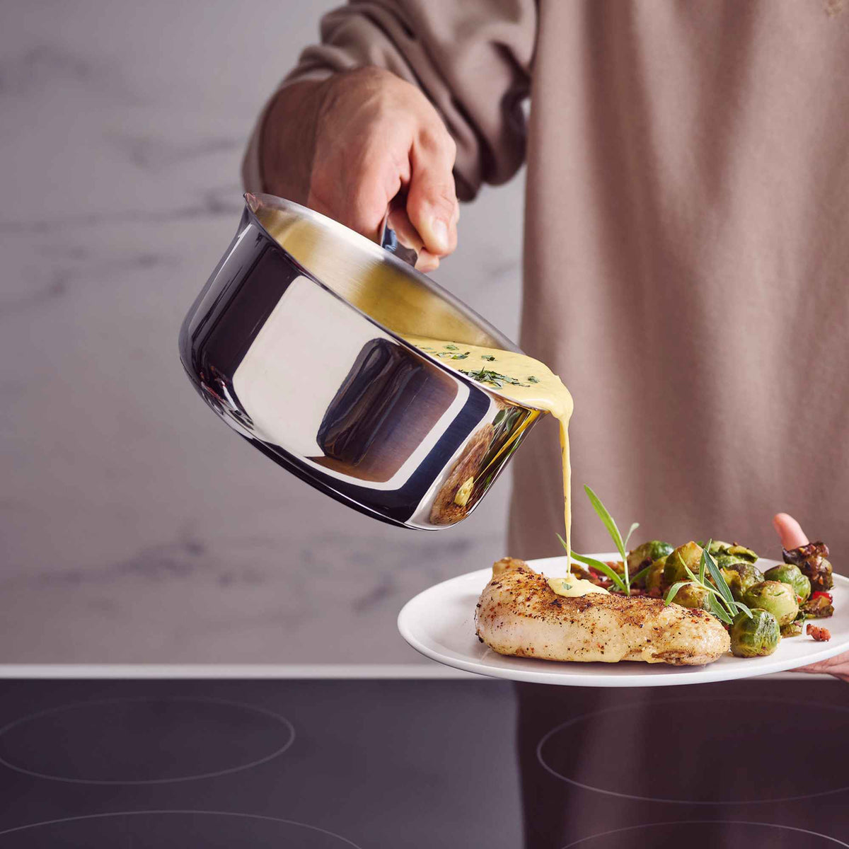 Home cook pouring food from an Alva stainless steel saucepan onto a prepared plate