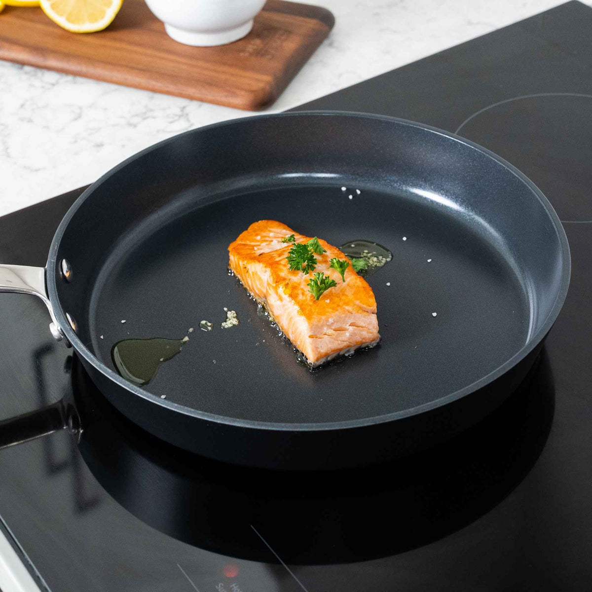 Salmon cooking in an Alva ceramic nonstick frying pan on a stovetop