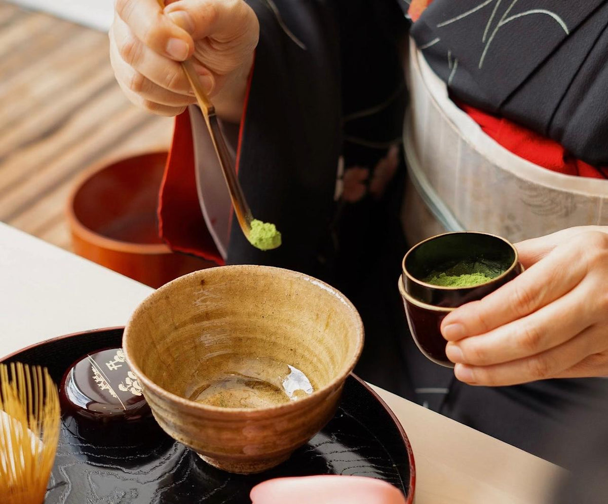 Traditional Japanese matcha preparation using a bamboo whisk and ceramic bowl
