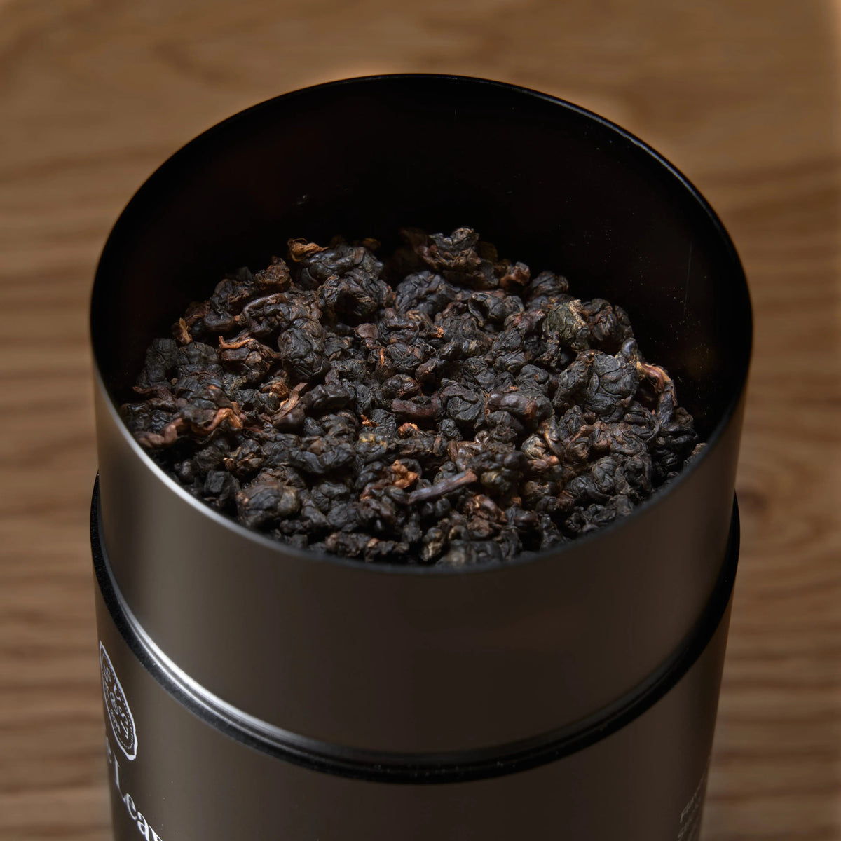 Close-up of dark roasted Taiwanese oolong tea leaves inside August Black Pearl aluminum tea caddy