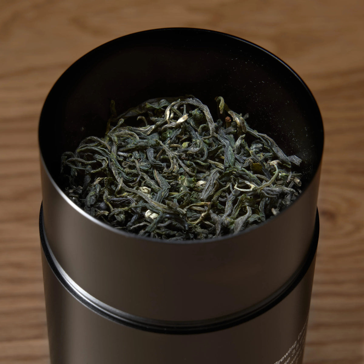 Close-up of organic Pi Lo Chun green tea leaves inside August Rare Leaves Emerald tin
