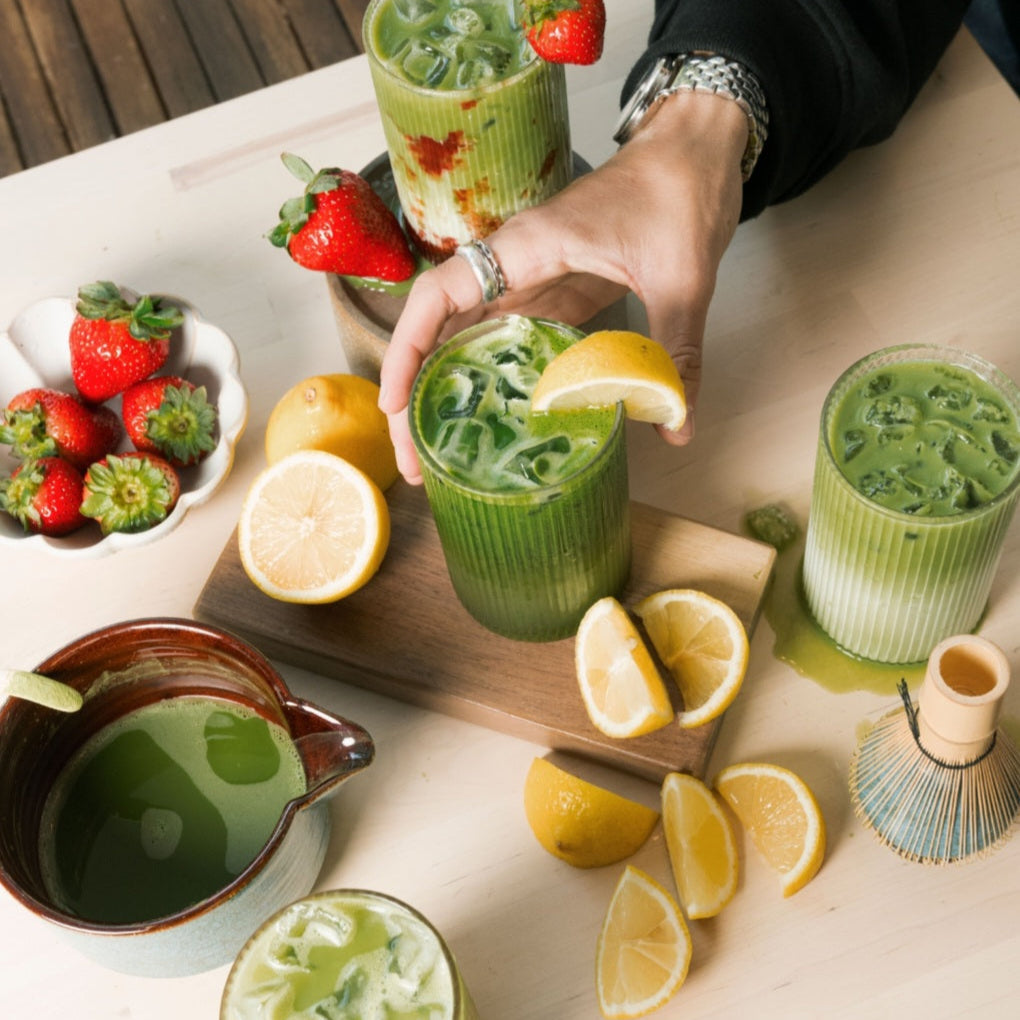 Iced matcha drinks with citrus fruit and fresh ingredients arranged on a table