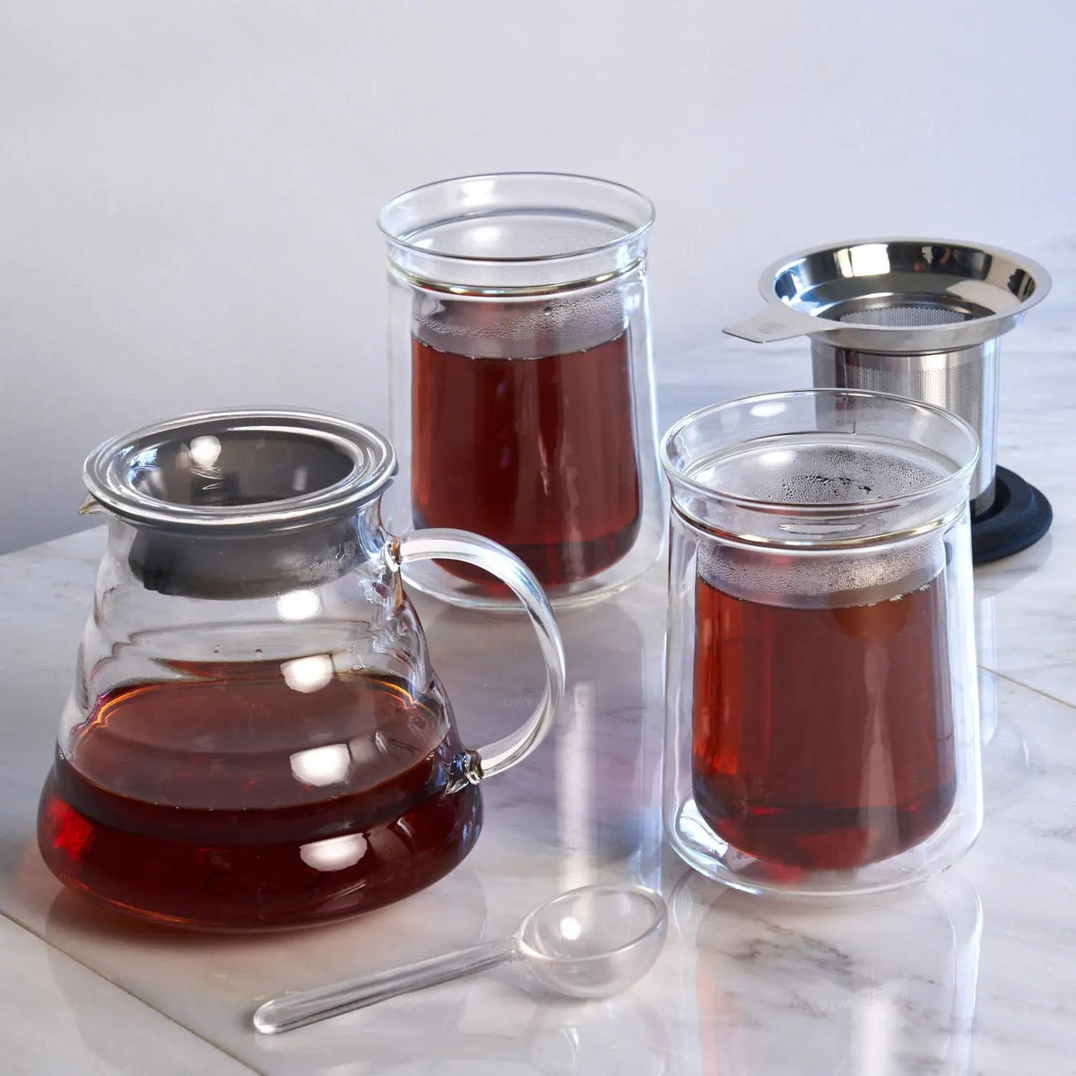 August Tea for Two glass teapot, tasting glasses and tea accessories displayed together