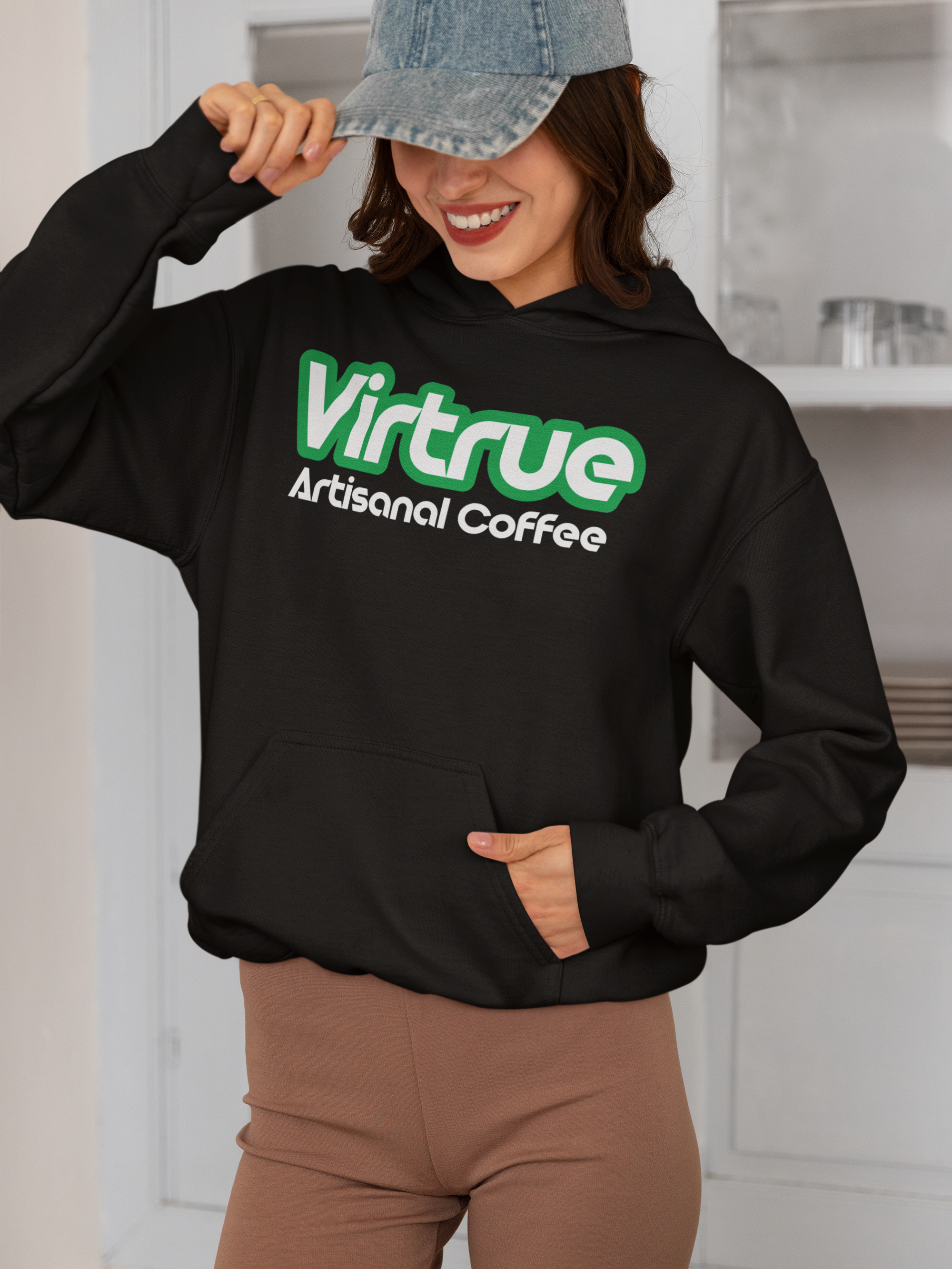 A person wearing a black unisex hooded sweatshirt with the 'Virtrue Artisanal Coffee' logo in green text on the front.